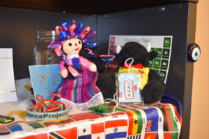 A doll and stuffed bear sit atop a banner of international flags