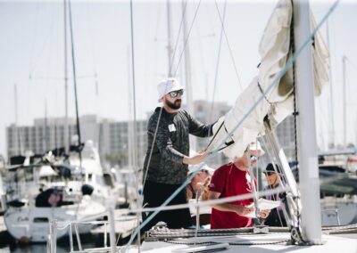 man adjusting sail on boat